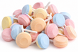 Unwrapped pastel Smarties lollipops in a bulk candy pile