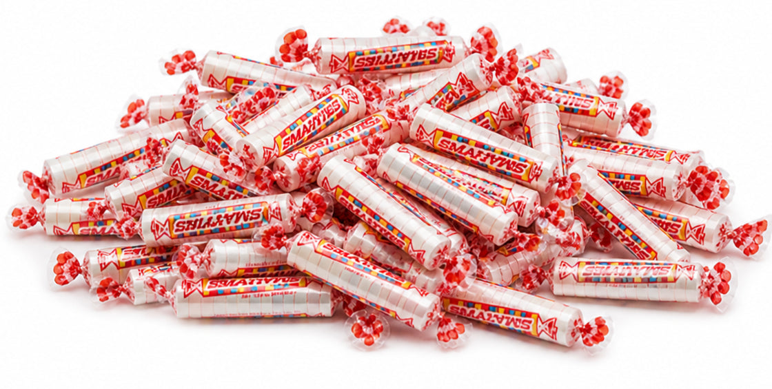 Bulk Smarties candy rolls, individually wrapped, poured out showing colorful assortment
