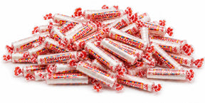 Bulk Smarties candy rolls, individually wrapped, poured out showing colorful assortment